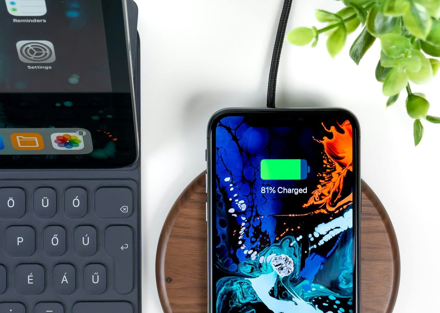 A smartphone charging on a wooden wireless charging pad, showing 81 percent charged